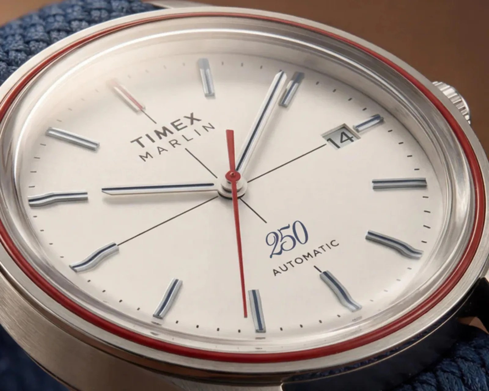 Close-up of a Timex Marlin automatic watch with a white dial, silver hour markers, red second hand, and date window.