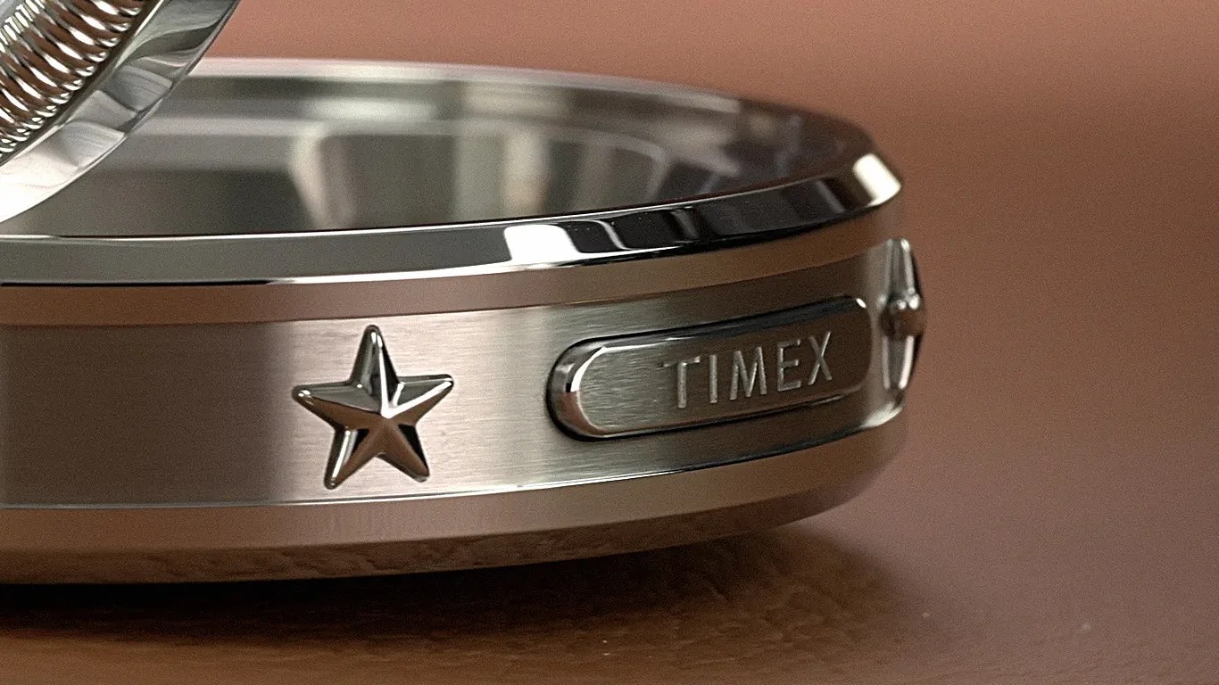 Close-up of a silver metal Timex watch case with a star emblem and brushed finish.
