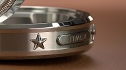 Close-up of a silver metal Timex watch case with a star emblem and brushed finish.