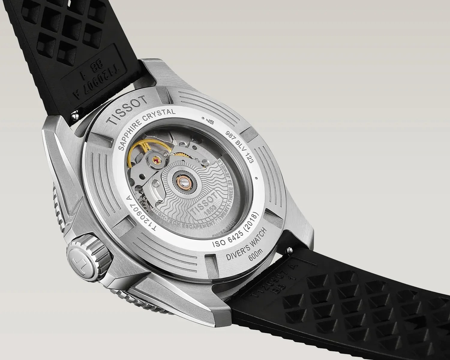 Back of a Tissot stainless steel diver's watch with visible automatic movement and black rubber strap.