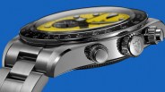 Close-up of a stainless steel wristwatch with a yellow dial, black bezel with white markings, and three crown buttons on the side.