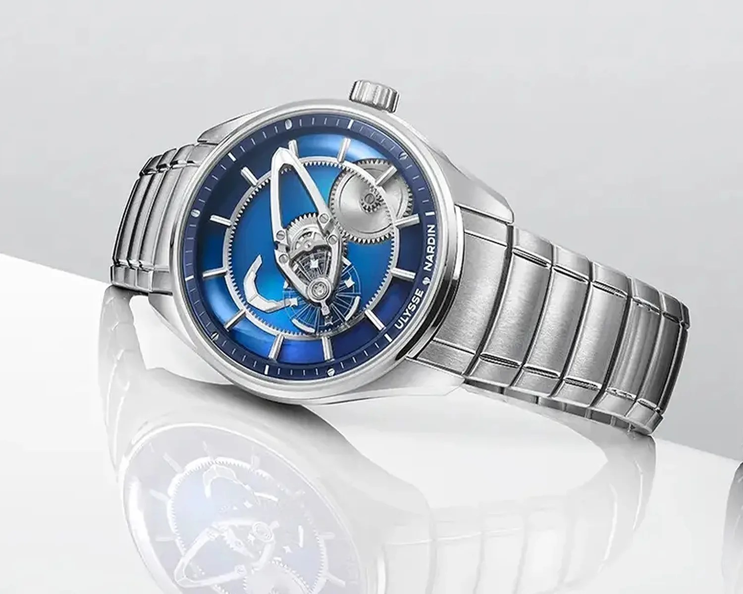 Silver Ulysse Nardin wristwatch with a blue dial and visible mechanical gears.
