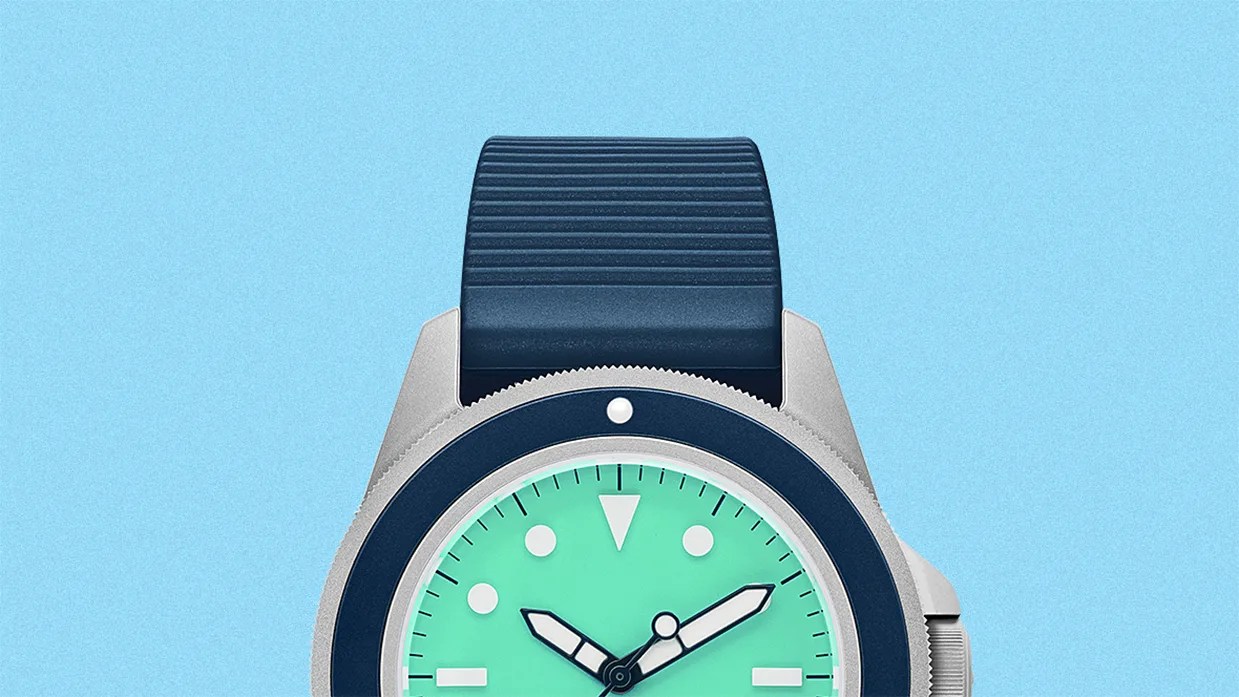 Silver watch with a blue bezel, turquoise dial, and blue ribbed silicone strap on a light blue background.
