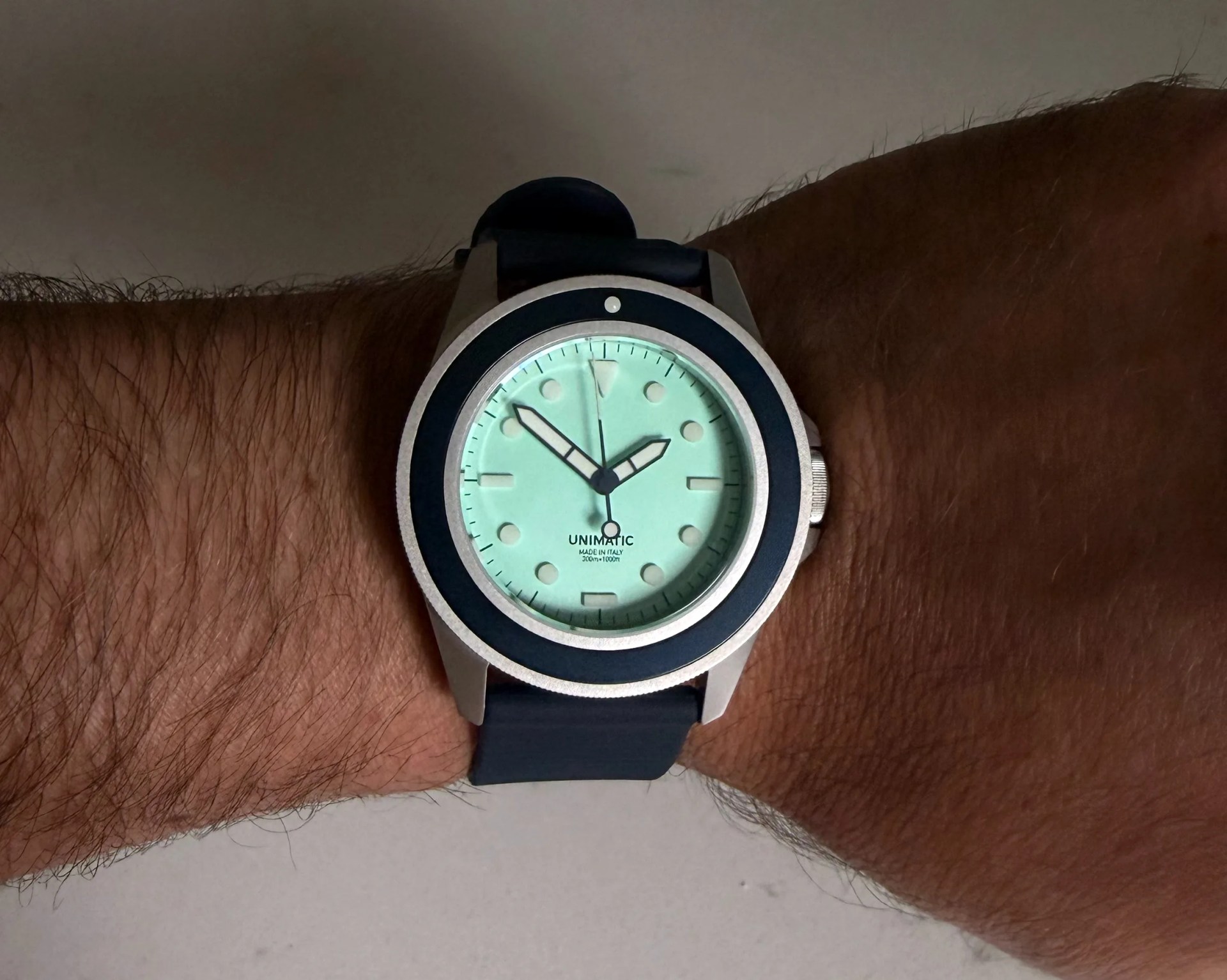 Wristwatch with a mint green dial, black bezel, and black strap worn on a wrist.
