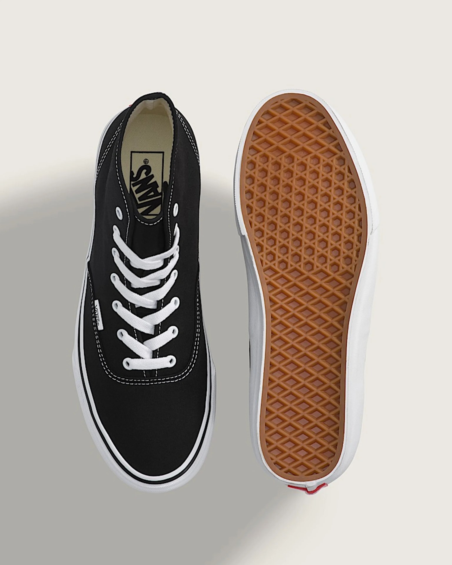 Pair of black Vans sneakers with white laces and white rubber soles, one showing the top and the other the gum sole.