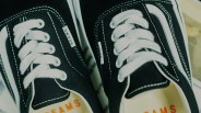 Close-up of black canvas sneakers with white laces and white side stripes, labeled "BEAMS" on the tongue tag.