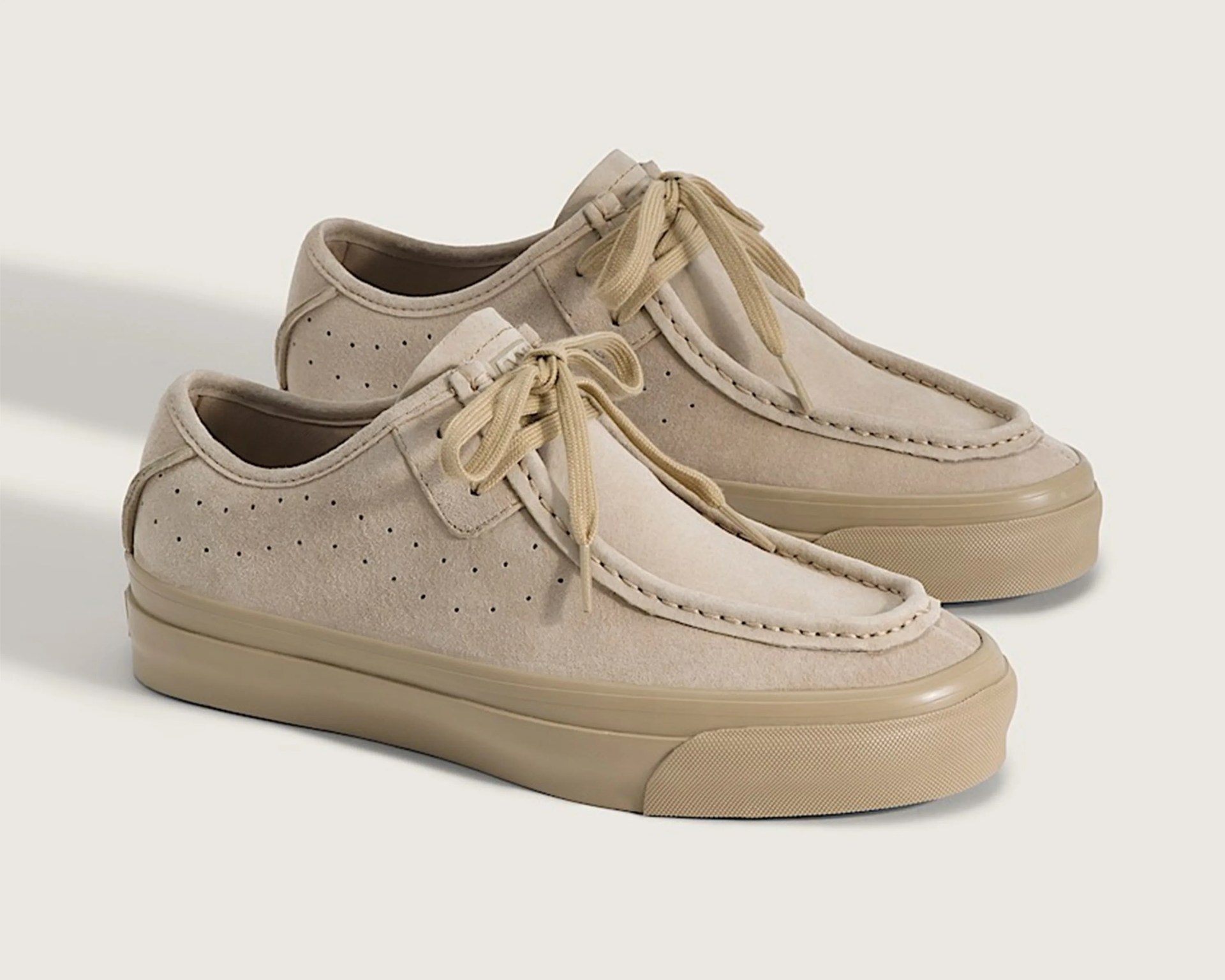 Pair of beige suede moccasin-style sneakers with perforated sides and rubber soles.