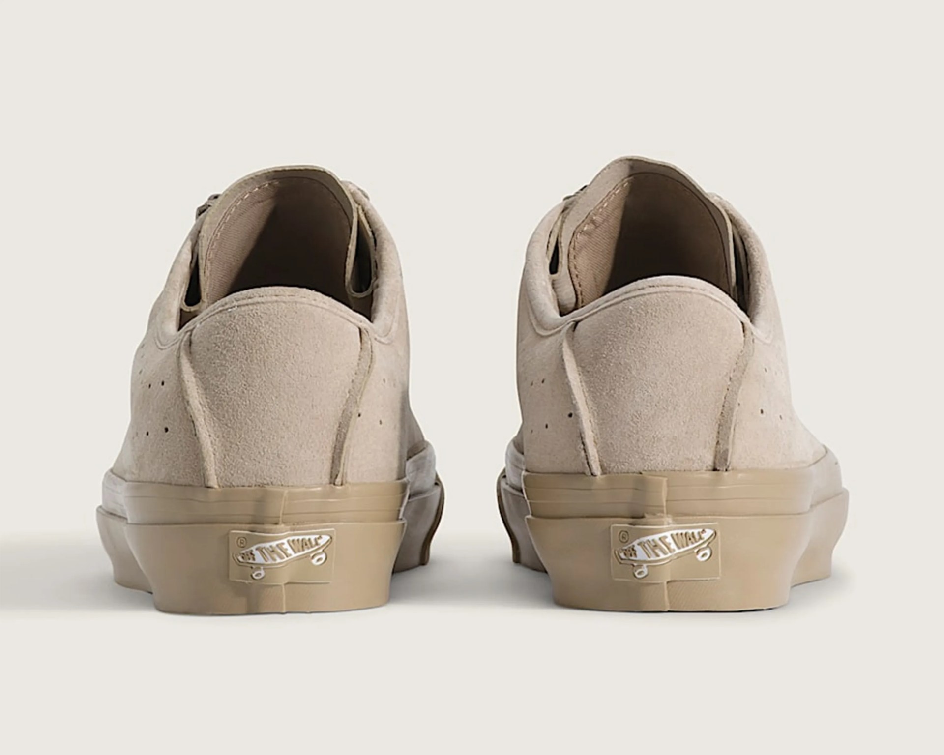 Pair of beige suede Vans sneakers viewed from the back showing "Off The Wall" logo on rubber soles.