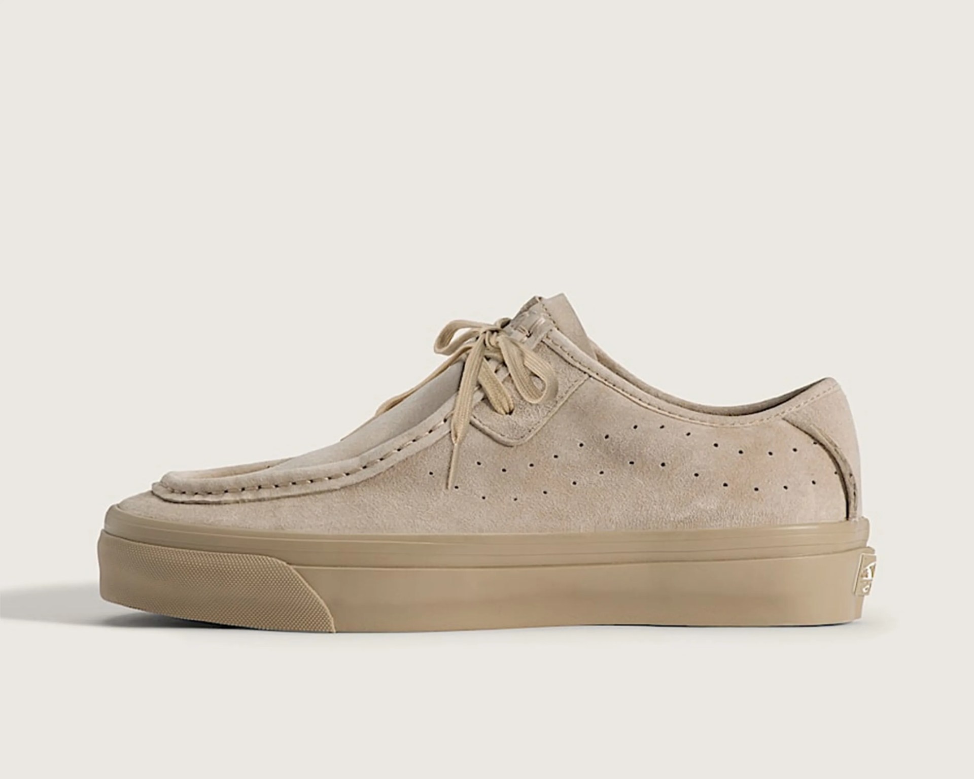 Beige suede lace-up shoe with perforated sides and a thick rubber sole.