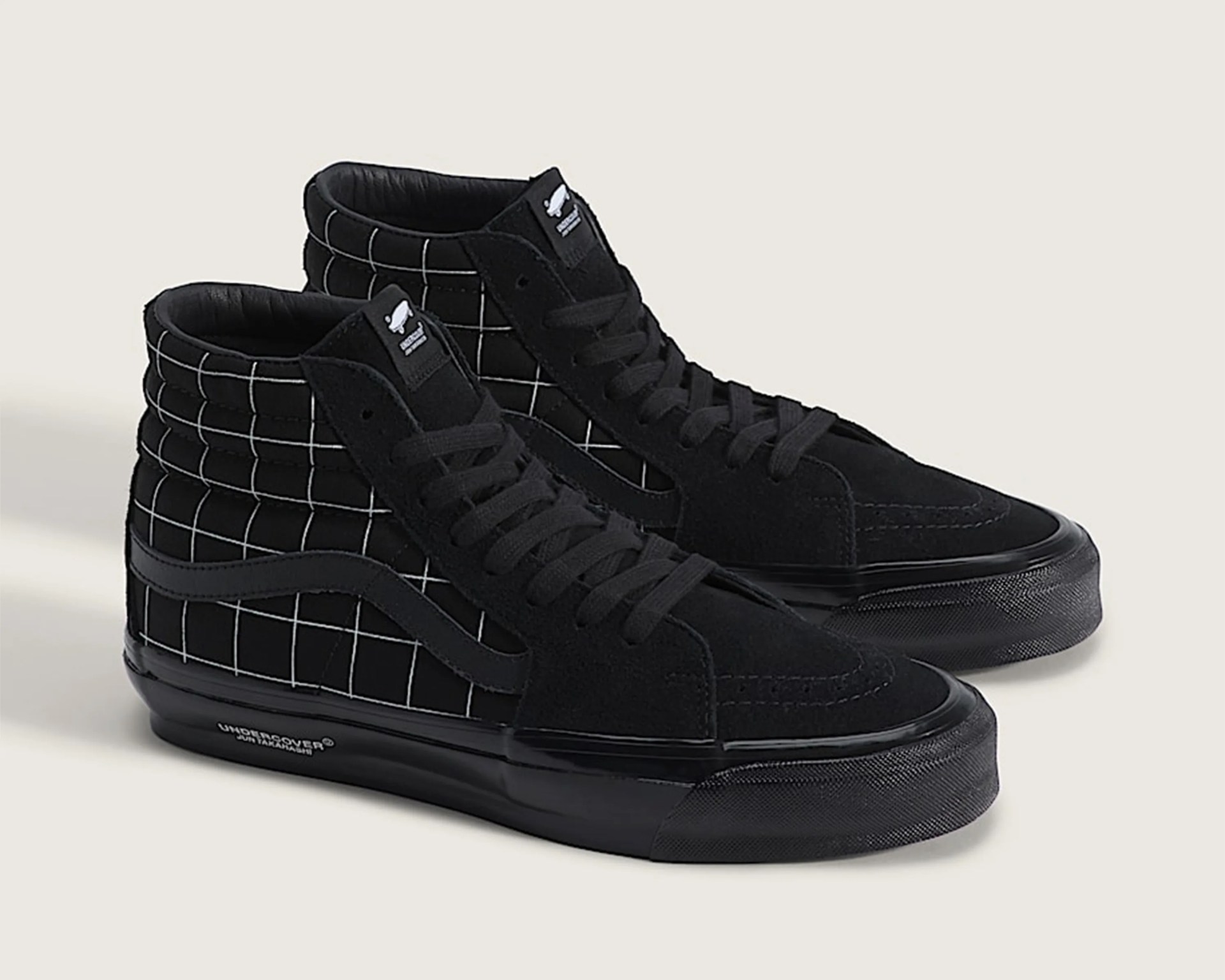 Pair of black high-top sneakers with white grid pattern on the sides and black soles.