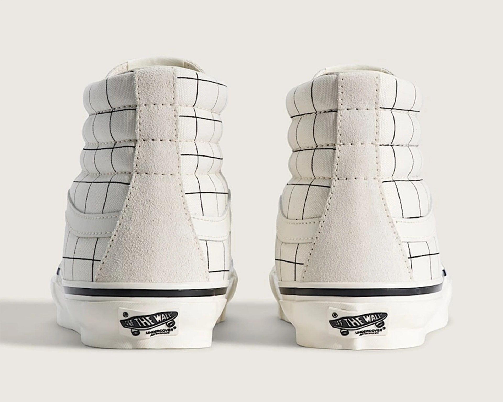 Pair of white high-top sneakers with black grid pattern and suede heel panels viewed from the back.