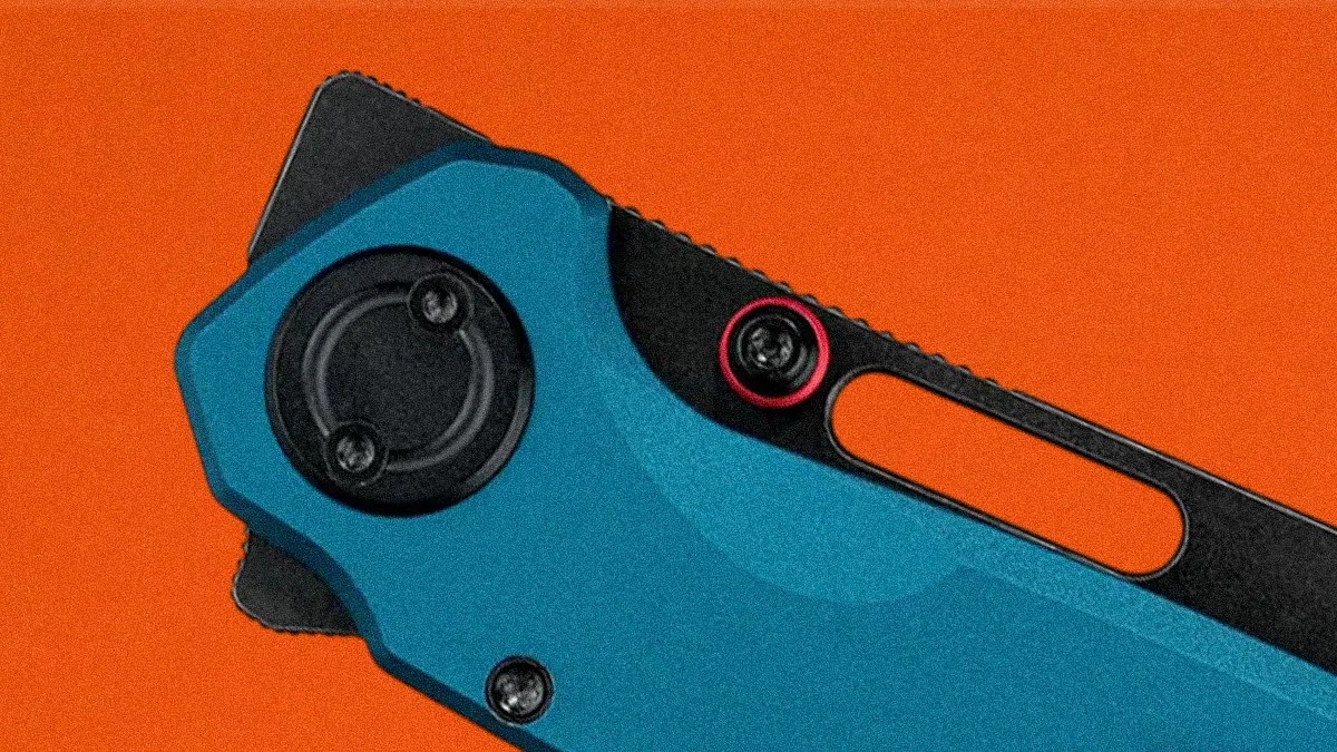 Close-up of a blue and black folding knife handle with visible screws and an orange background.