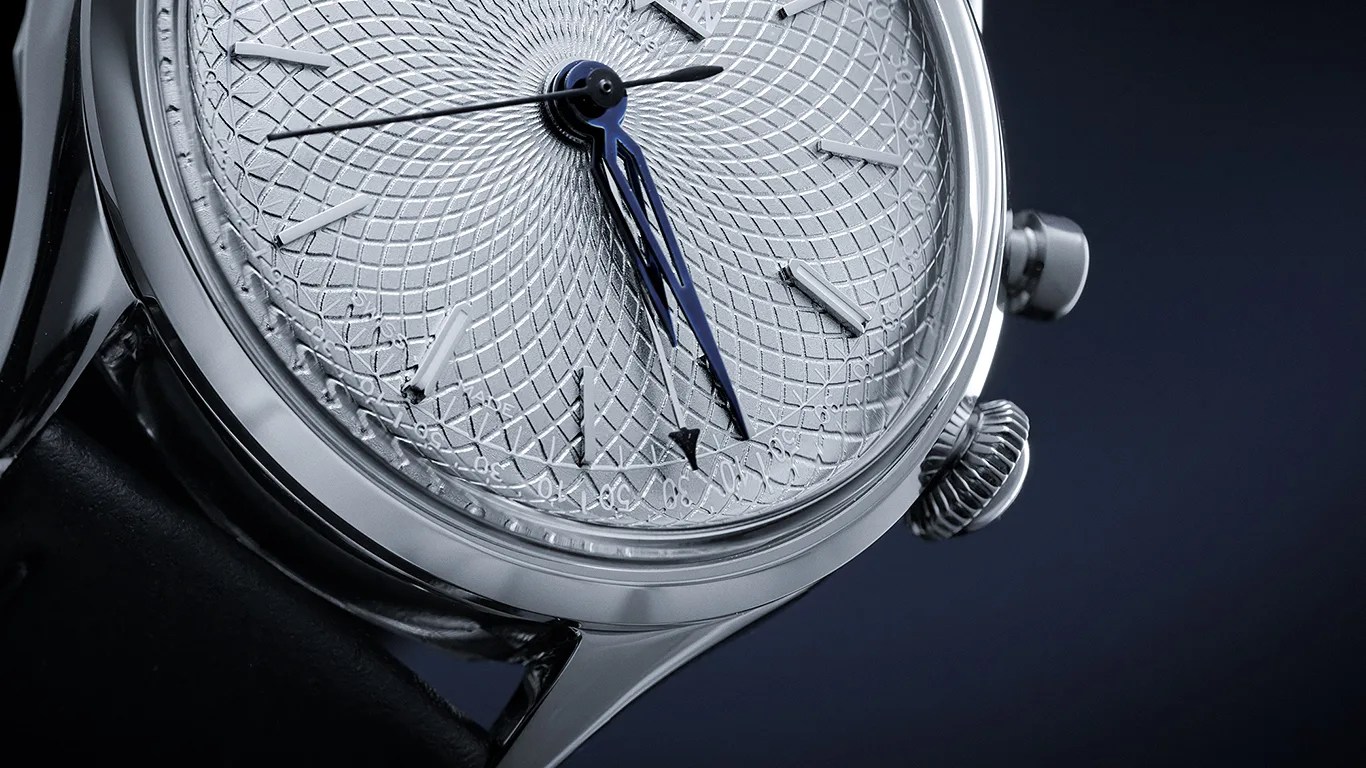 Close-up of a silver watch face with intricate geometric pattern, blue hands, and black leather strap.