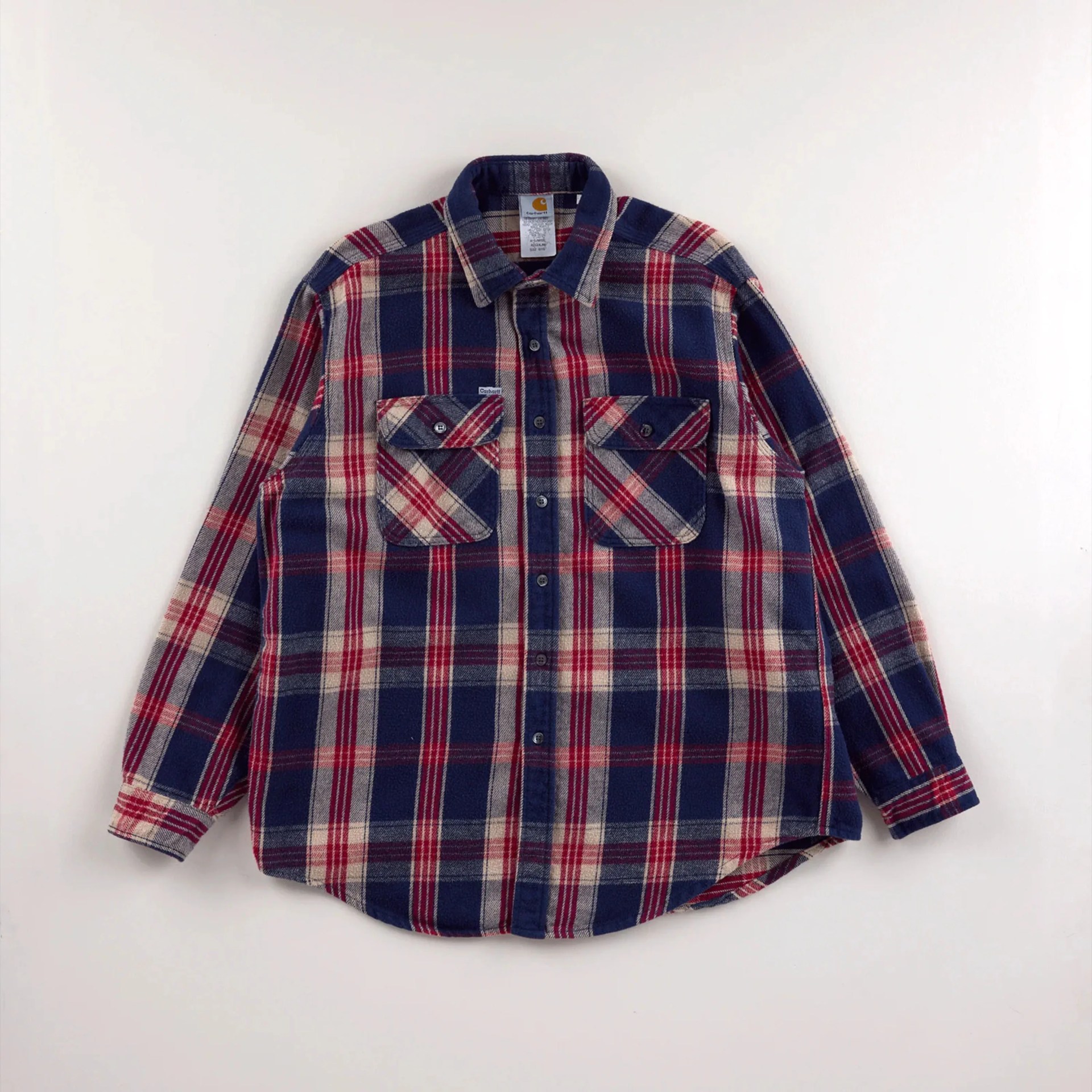 Blue, red, and beige plaid button-up shirt with two chest pockets laid flat on a white surface.