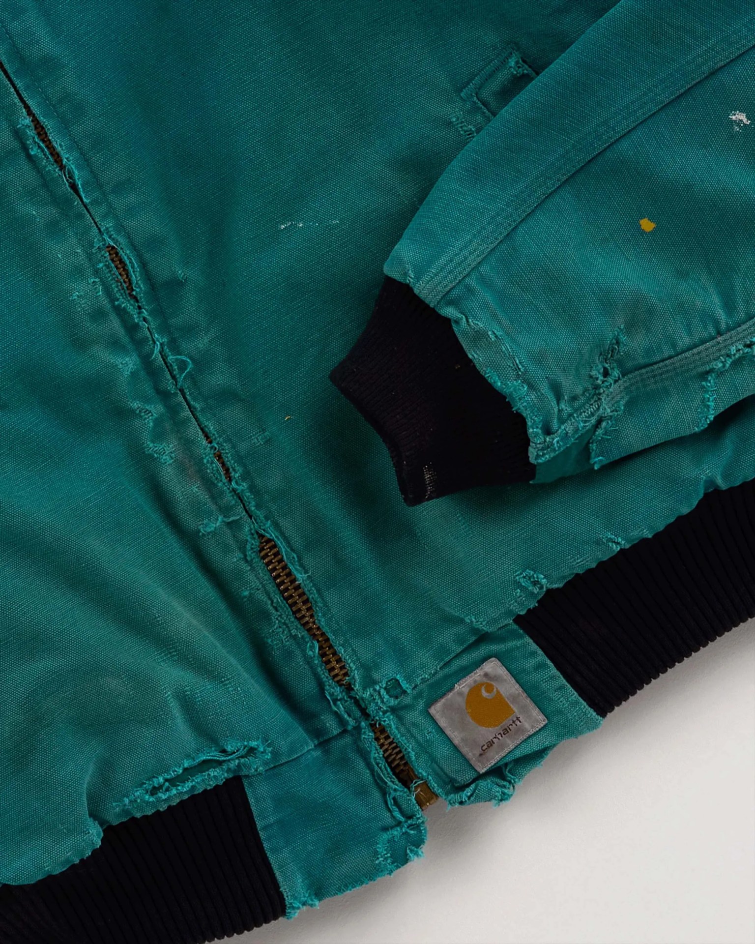 Teal Carhartt jacket with visible wear, frayed edges, black ribbed cuffs, and a zipper.