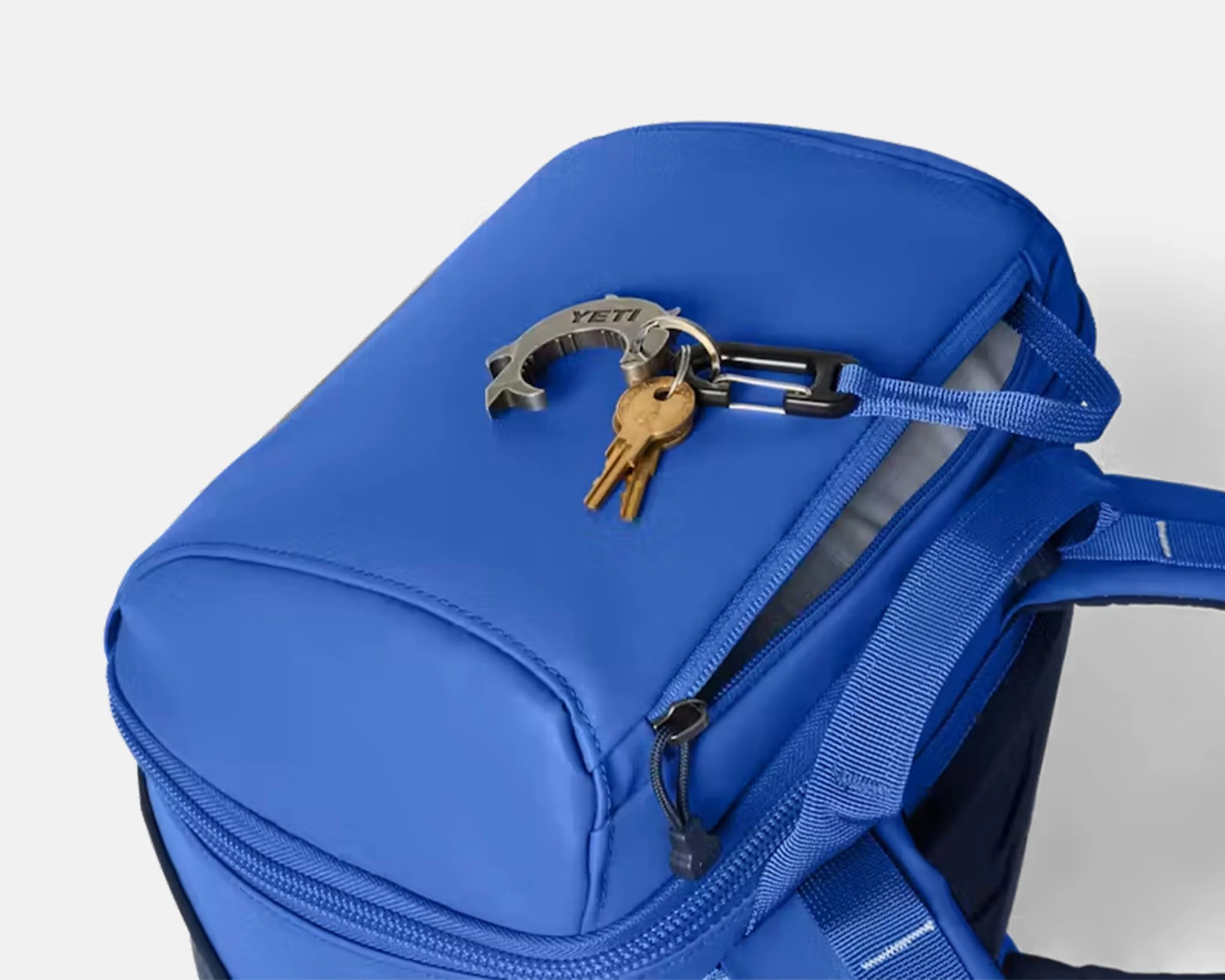 Blue backpack with a zipper and a keychain holding two keys attached to a strap.