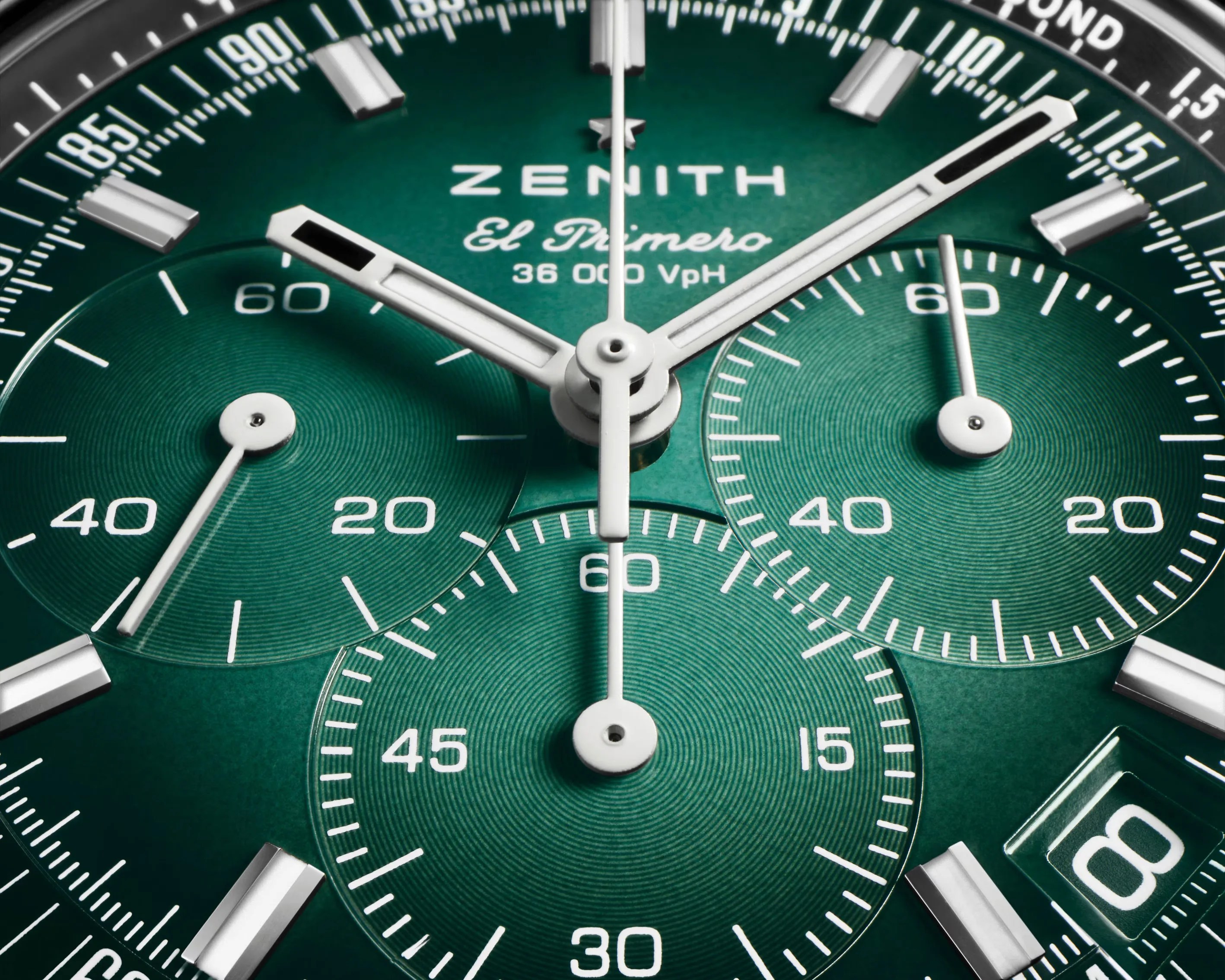 Close-up of a green Zenith El Primero watch dial with white hands and silver hour markers.