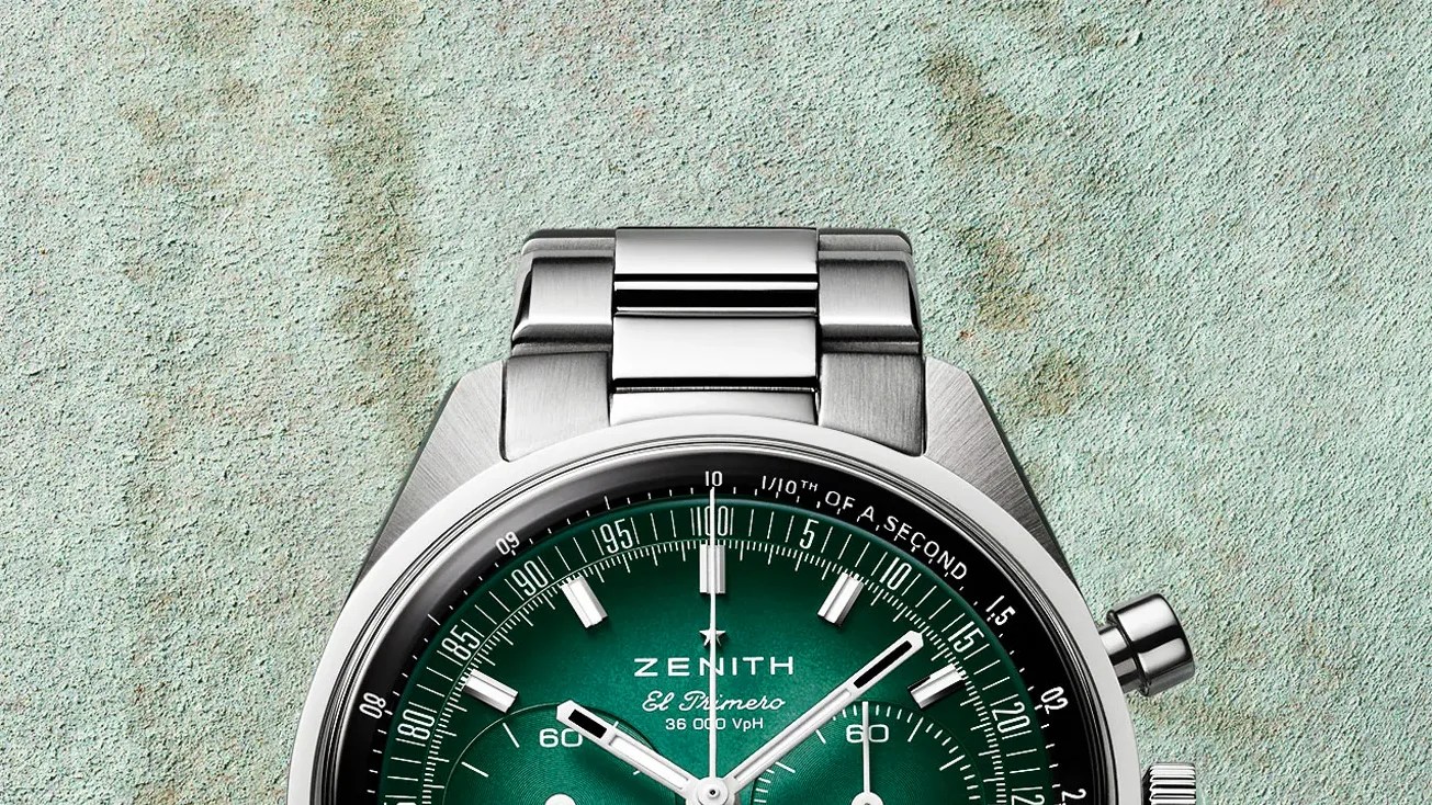 Silver metal Zenith El Primero chronograph watch with green dial and tachymeter scale on textured surface.
