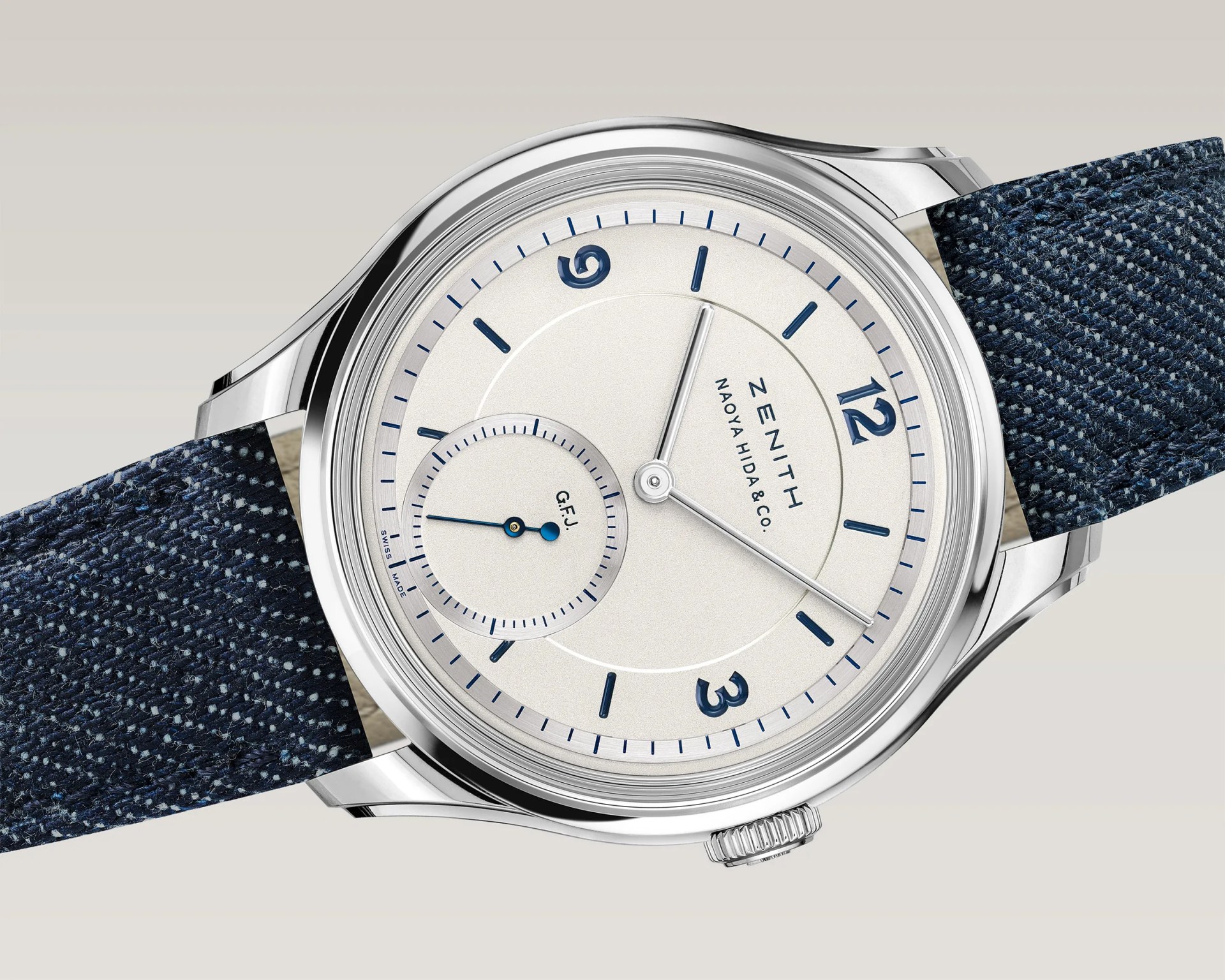 Silver Zenith wristwatch with white dial, blue hour markers, subdial, and textured dark blue fabric strap.