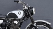 Silver and black vintage Honda motorcycle with a round headlight and knobby tires against a gray wall.