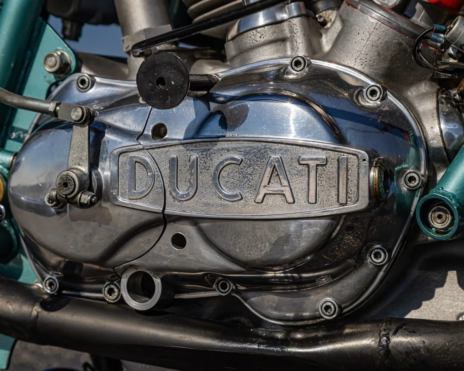 Close-up of a polished metal Ducati motorcycle engine cover with visible bolts and mechanical parts.