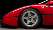 Close-up of a red Ferrari front wheel with silver five-spoke rim and Brembo brake caliper.