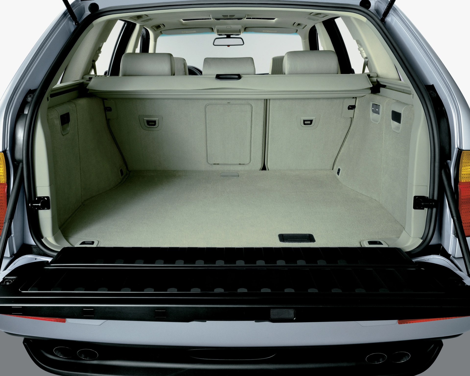 Spacious beige carpeted car trunk with rear seats and retractable cargo cover.
