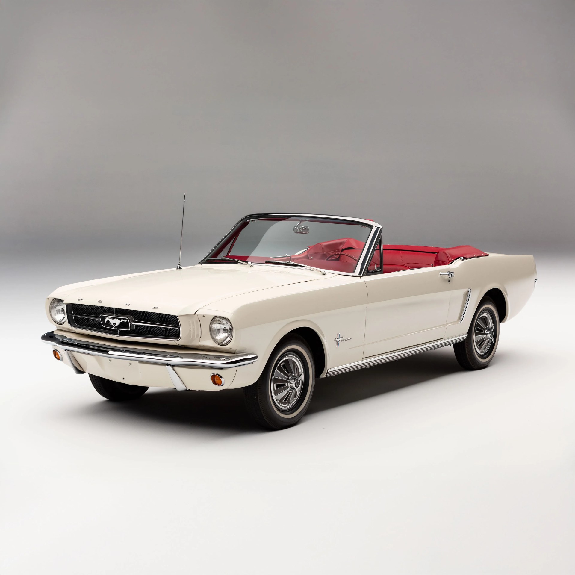 Cream-colored classic Ford Mustang convertible with red leather interior and chrome details.
