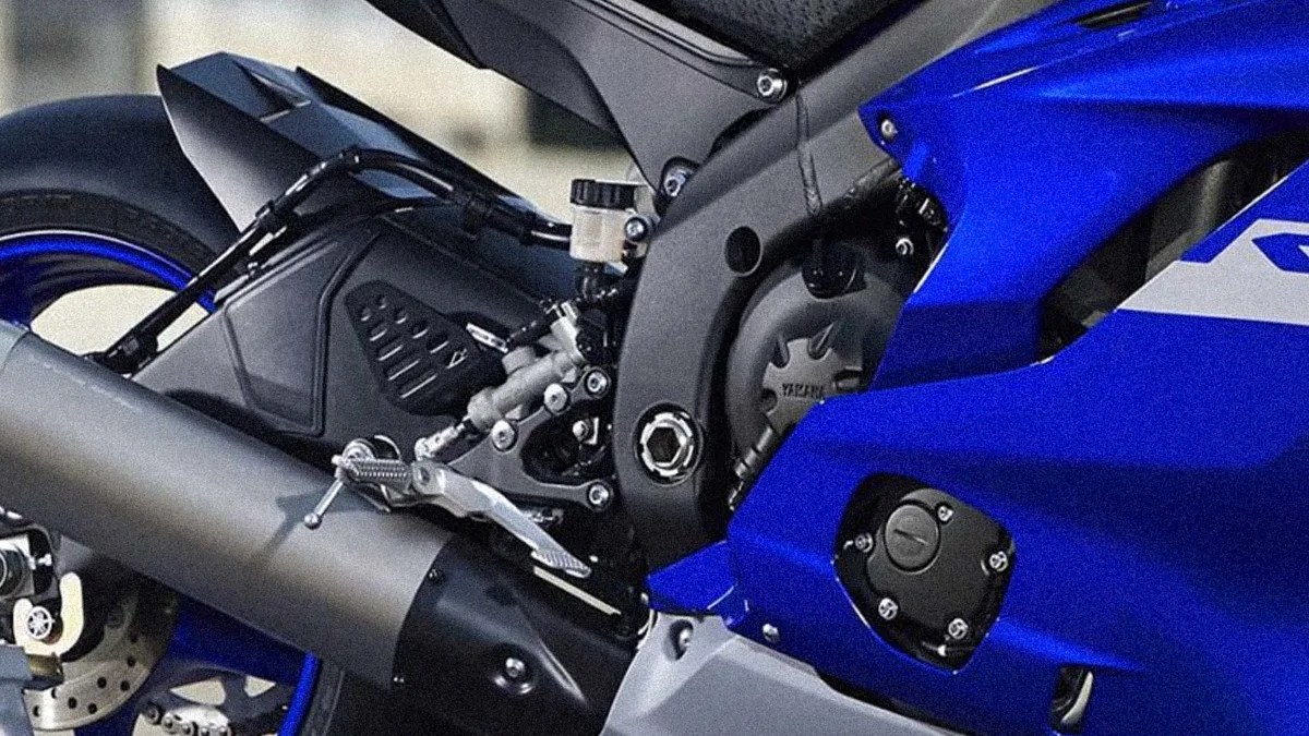 Close-up of the exhaust pipe, footpeg, and engine area on a blue Yamaha motorcycle.