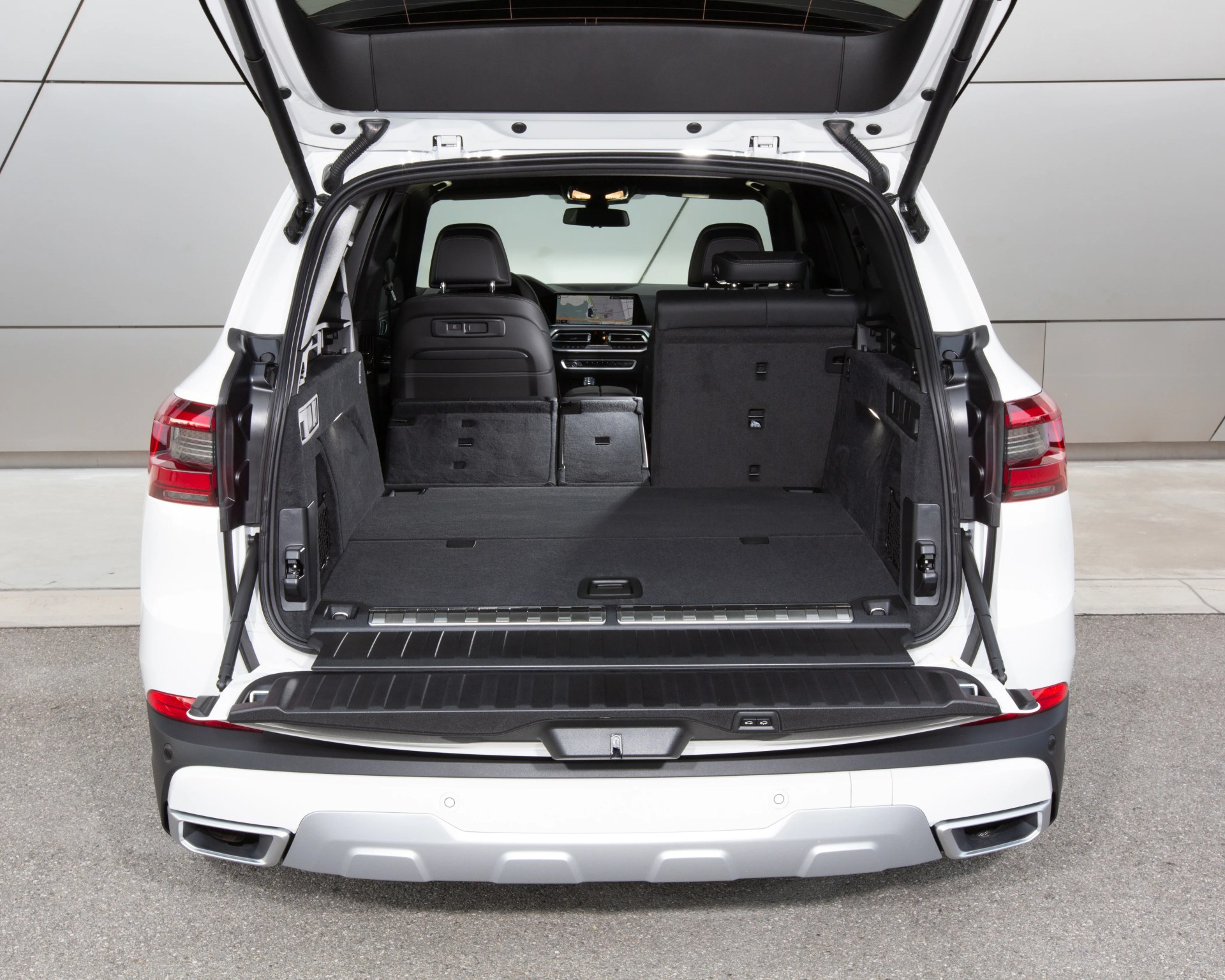 Open rear cargo area of a white SUV with black interior and partially folded rear seats.