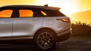 Silver SUV rear side with black roof and alloy wheel parked on gravel at sunset.