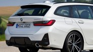White BMW 320d station wagon rear with black diffuser, dual exhaust, and black alloy wheels on a rural road.