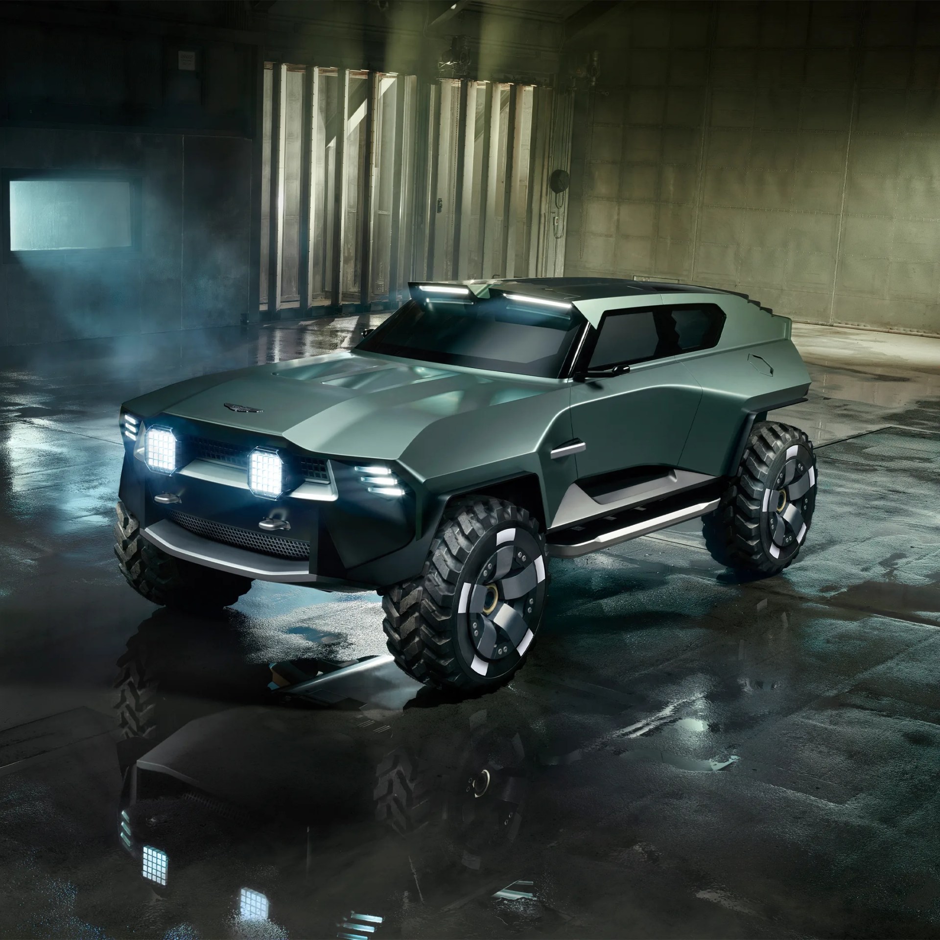 Matte green futuristic off-road vehicle with large rugged tires and bright LED lights in a dim industrial setting.