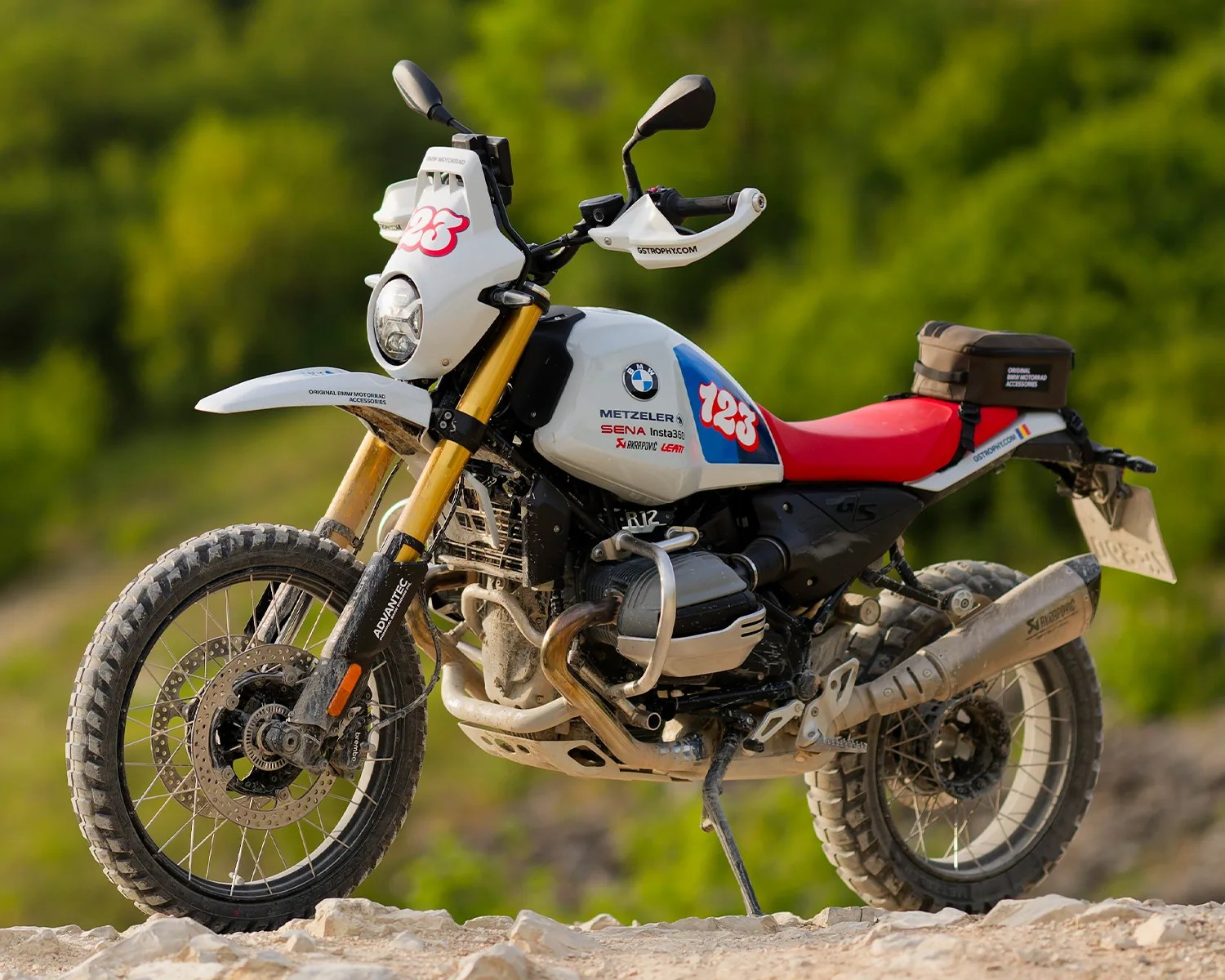 White BMW R1200 GS adventure motorcycle with red seat and off-road tires on rocky terrain.