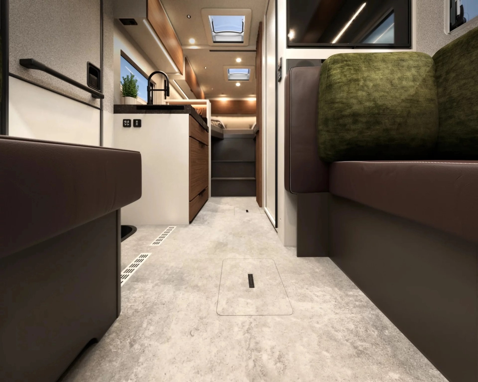 Interior view of a modern RV with brown leather seating, green cushions, a kitchen area with wooden cabinets, and skylights.