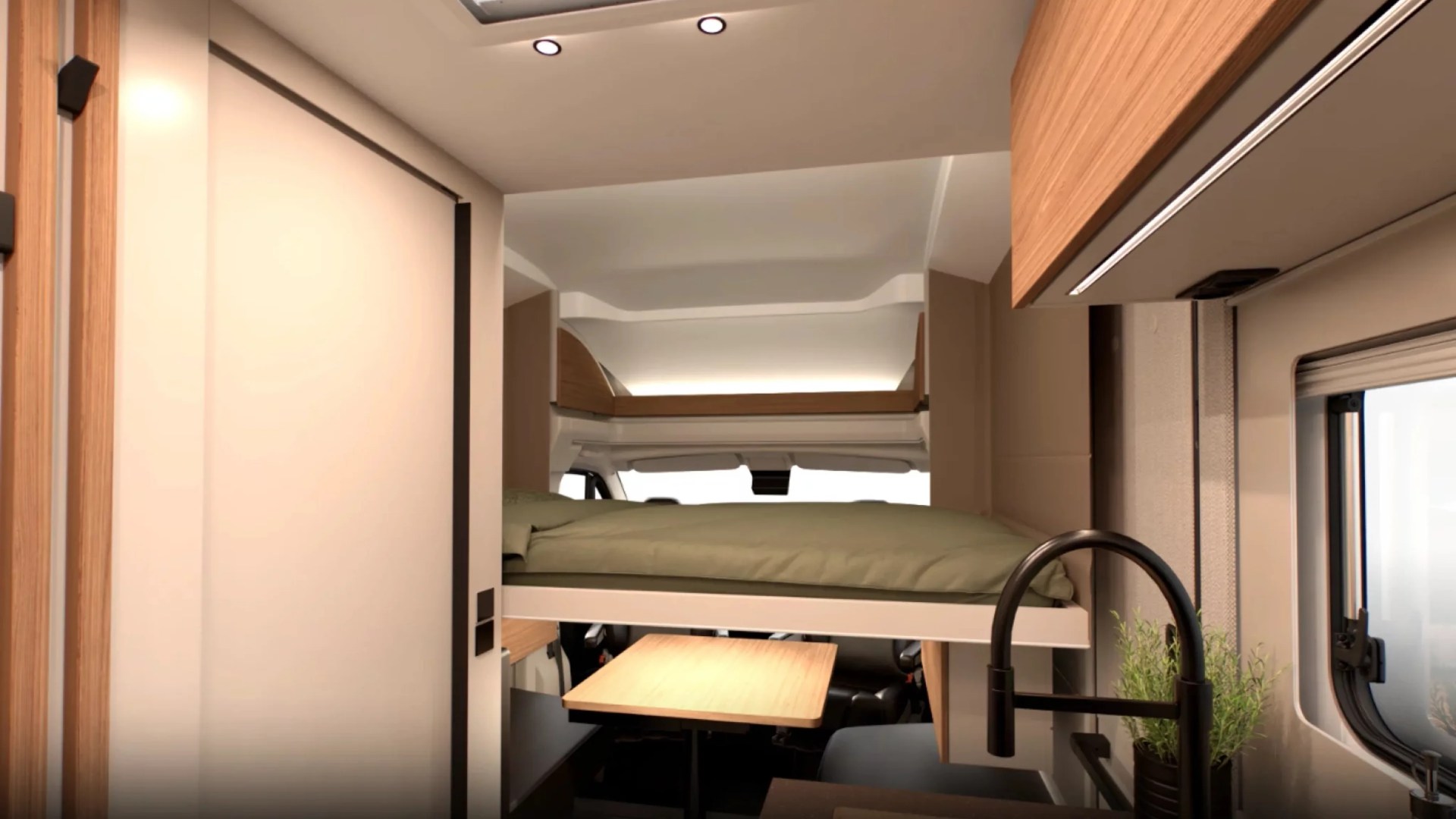 Compact camper interior with elevated bed, wooden table, black faucet, and window with potted plant.