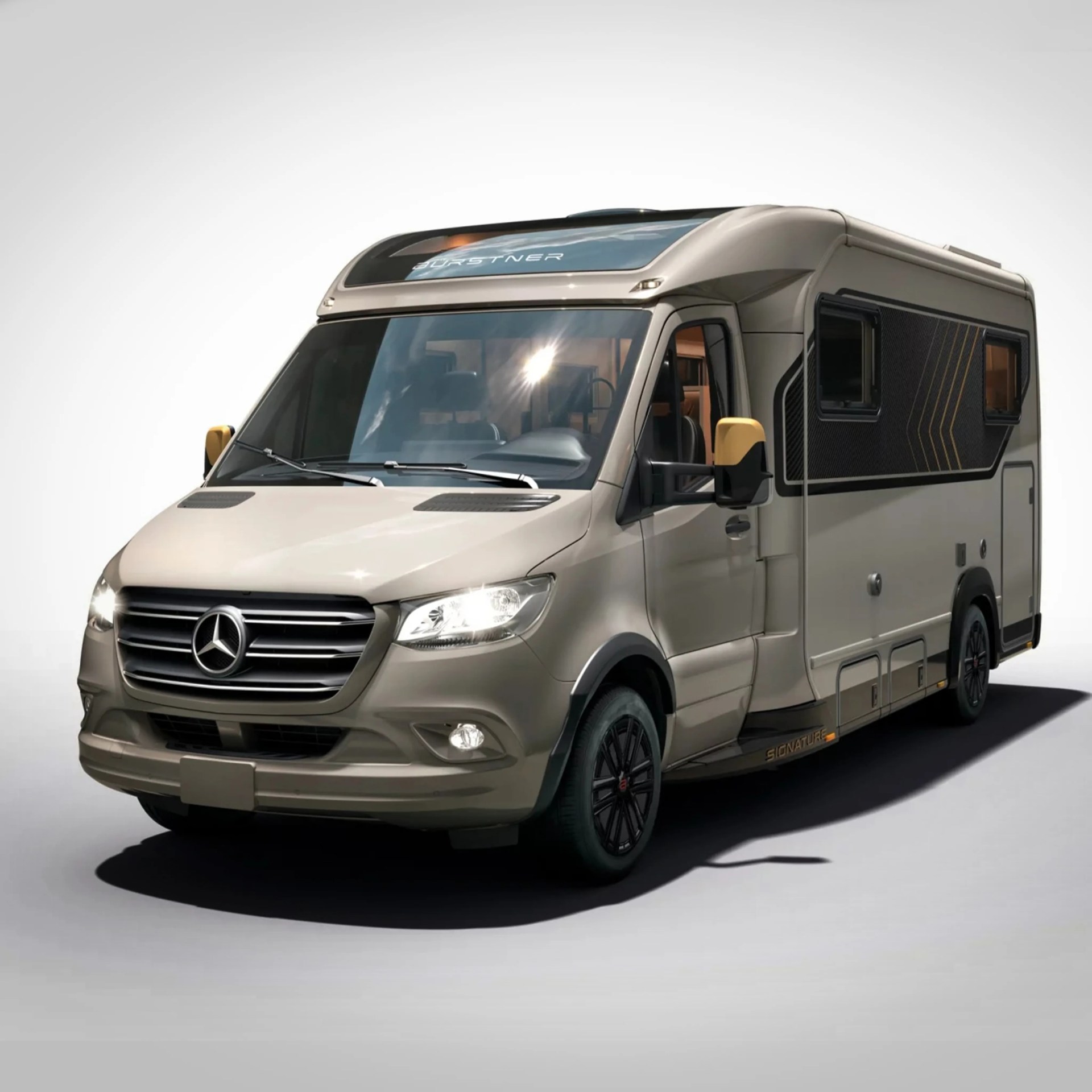 Beige Mercedes-Benz motorhome with black grille, yellow side mirrors, and black wheels.