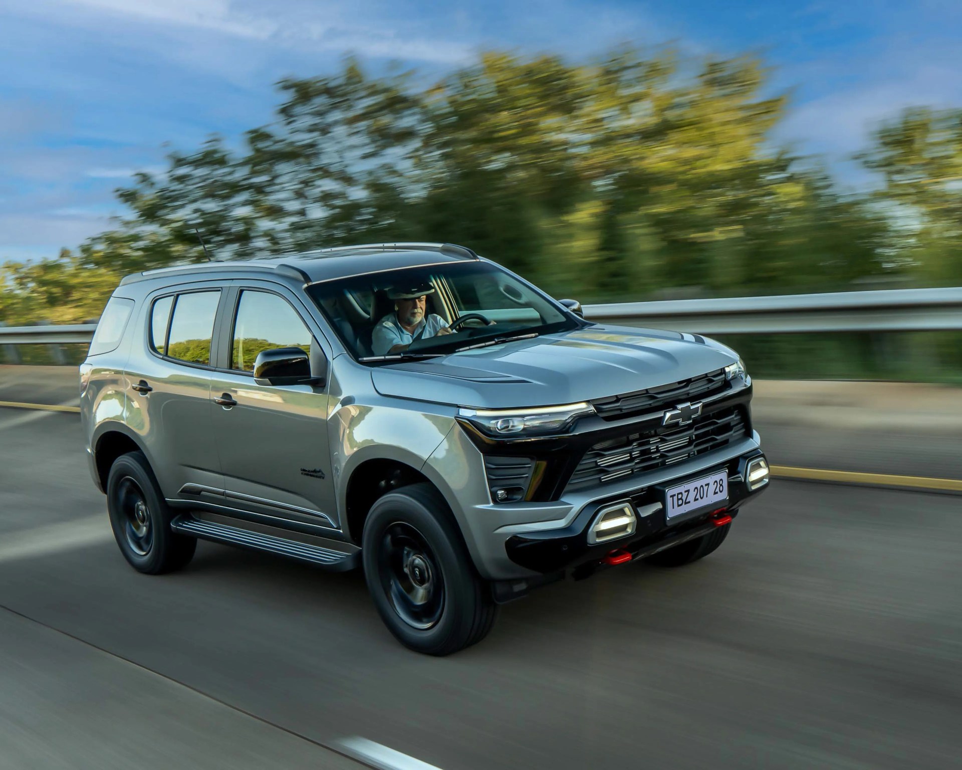 Silver Chevrolet SUV driving on a highway with a person visible inside the vehicle.