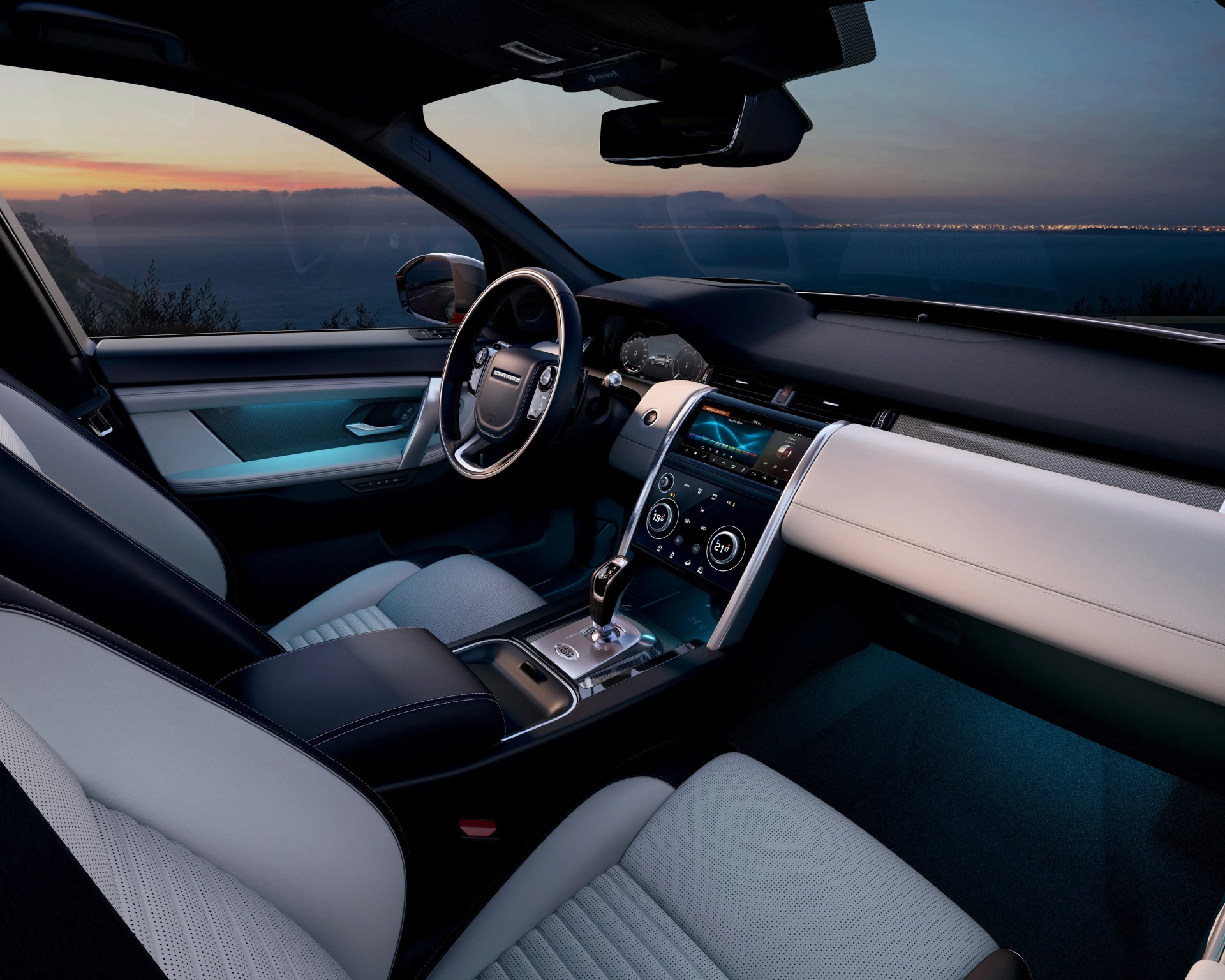 Luxury car interior with black and white leather seats, digital dashboard, and sunset view through the window.