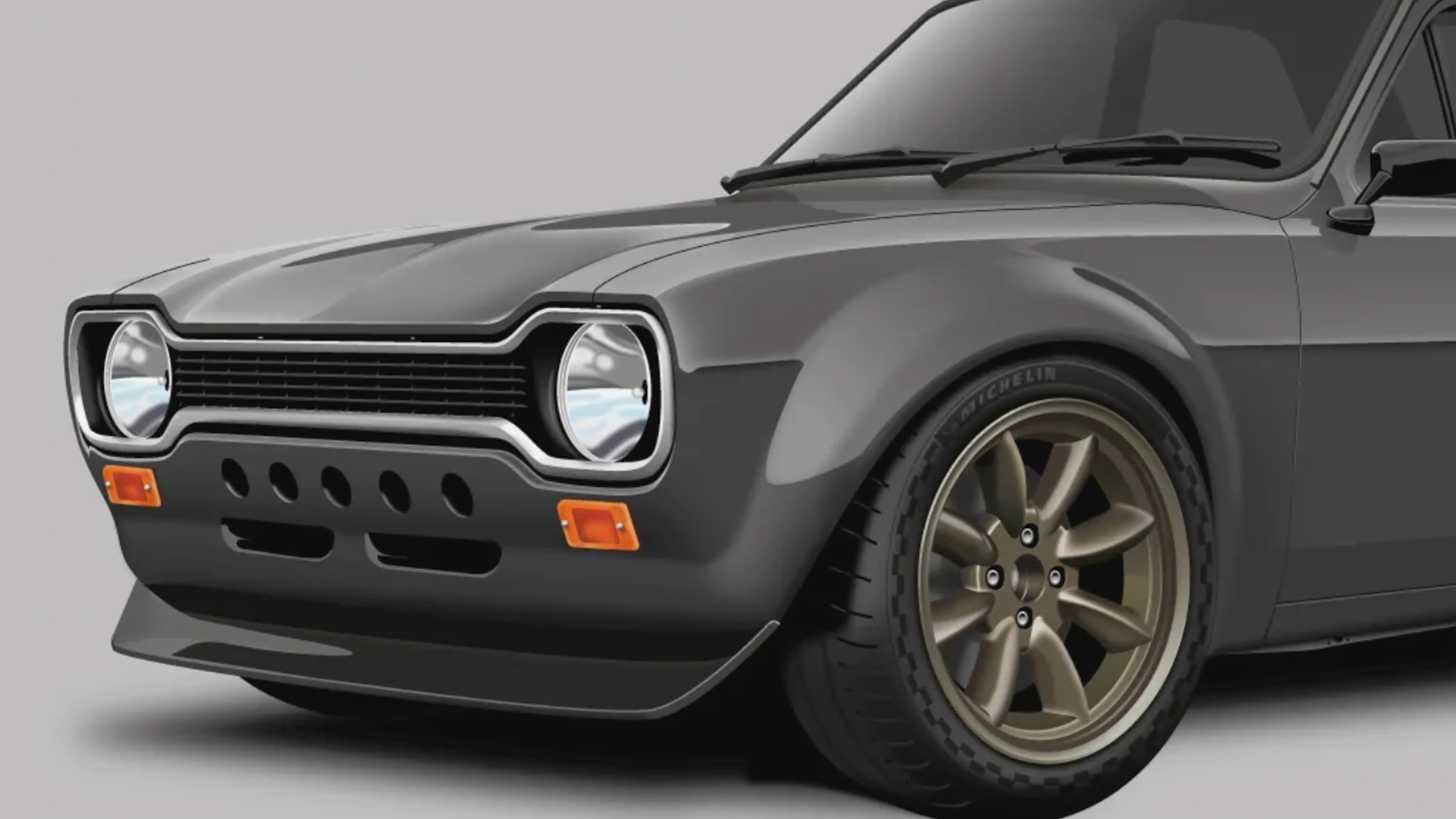 Front side view of a dark gray classic car with round headlights, bronze alloy wheels, and Michelin tires.