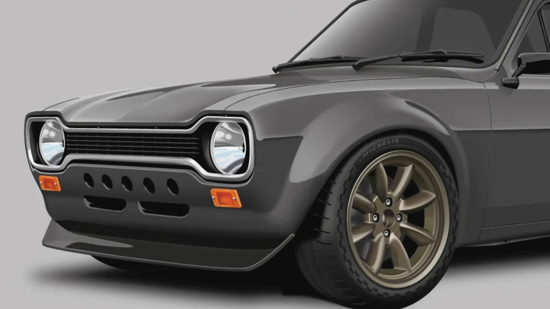 Front side view of a dark gray classic car with round headlights, bronze alloy wheels, and Michelin tires.
