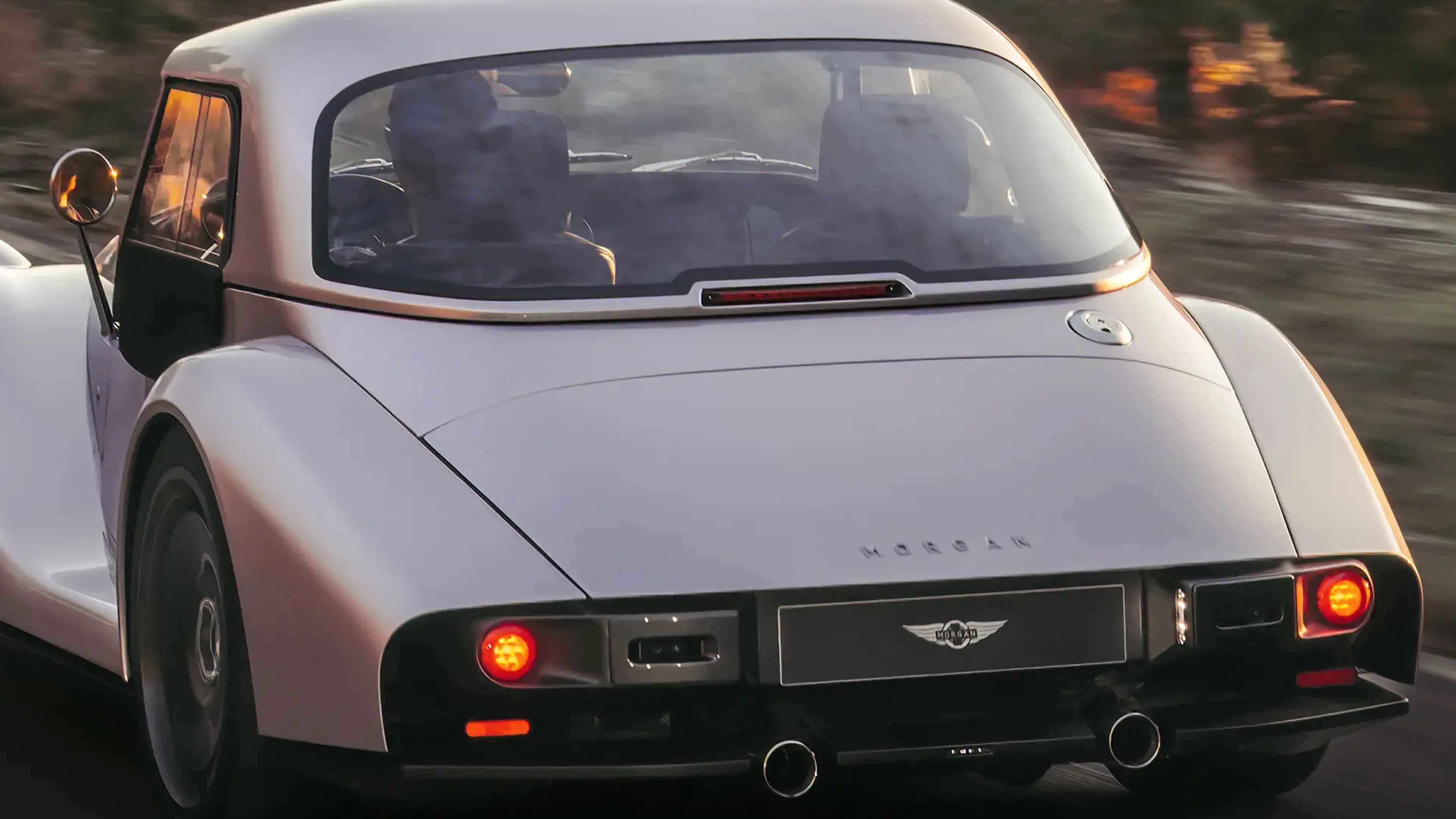 Rear view of a white Morgan sports car with round taillights and a visible Morgan logo on the trunk.