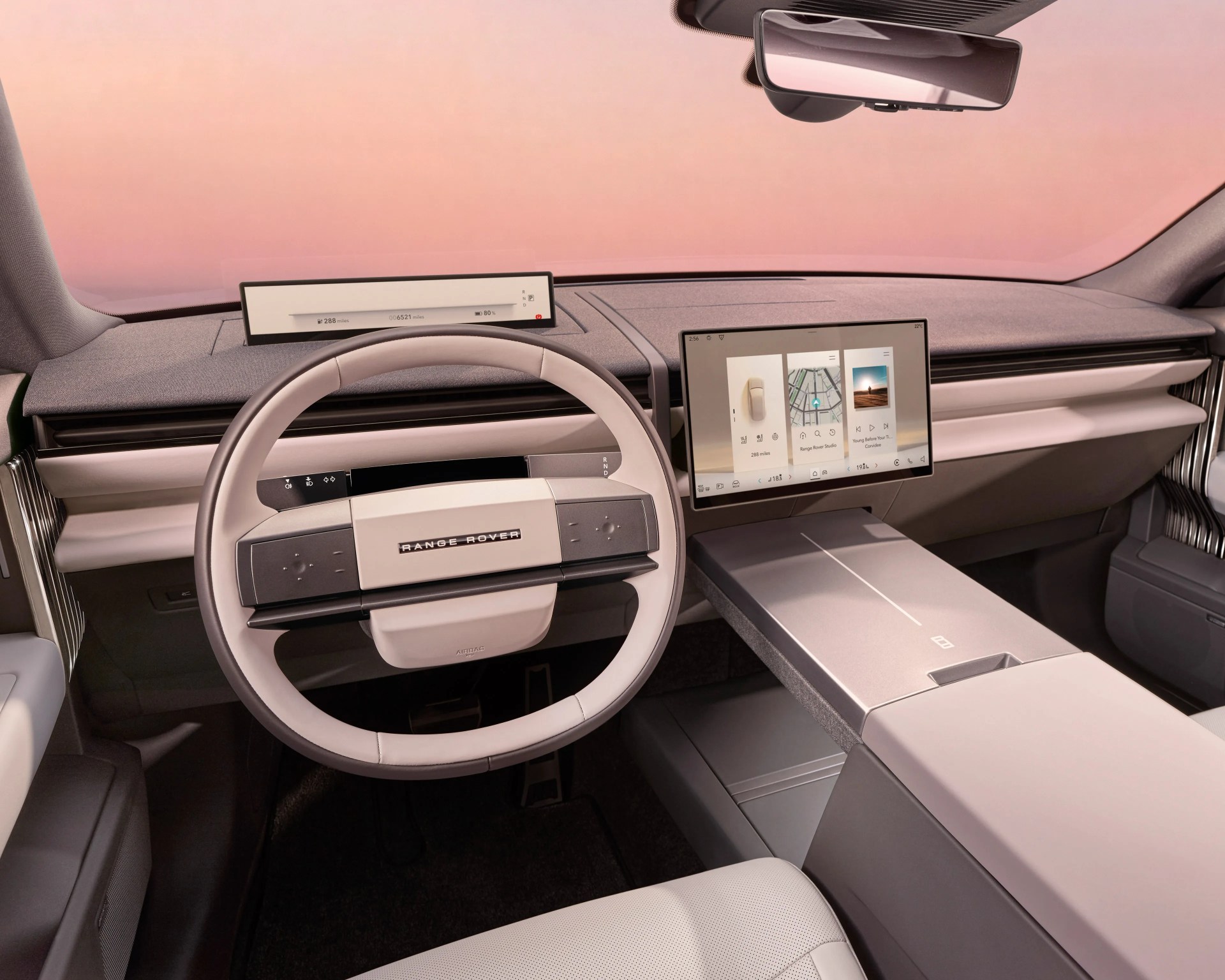 Range Rover car interior with beige steering wheel, digital dashboard, and touchscreen display on a light gray dashboard.