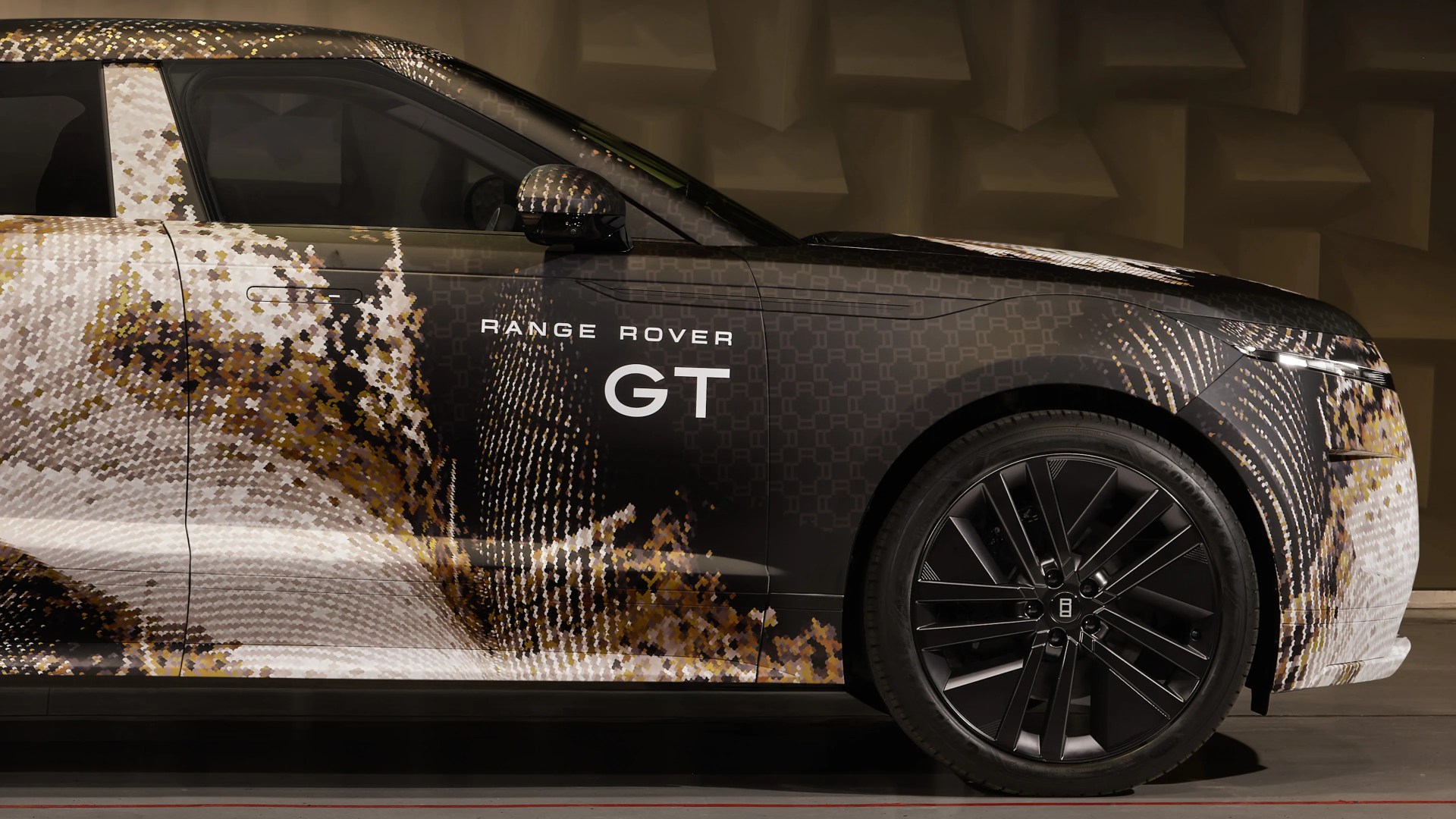 Side view of a Range Rover GT with a pixelated camouflage wrap and black alloy wheels.