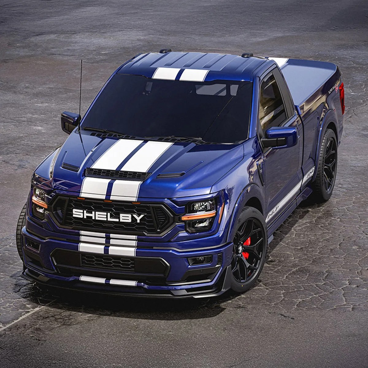 Blue Shelby pickup truck with white racing stripes and black wheels on cracked pavement.