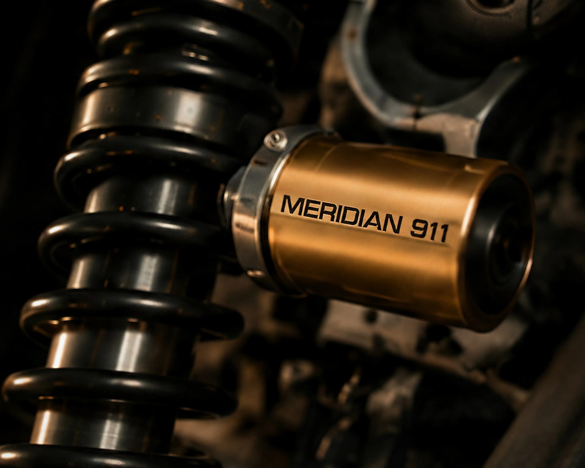 Close-up of a black coil spring suspension with a gold-colored component labeled "MERIDIAN 911.