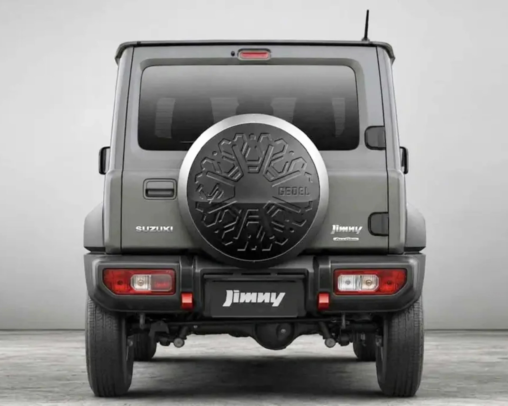 Rear view of a gray Suzuki Jimny with a spare tire cover featuring a snowflake design and "GEDEL" text.