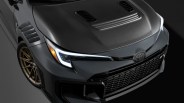Close-up of a dark gray Toyota car front with carbon fiber hood, bronze alloy wheel, and LED headlight on a black background.