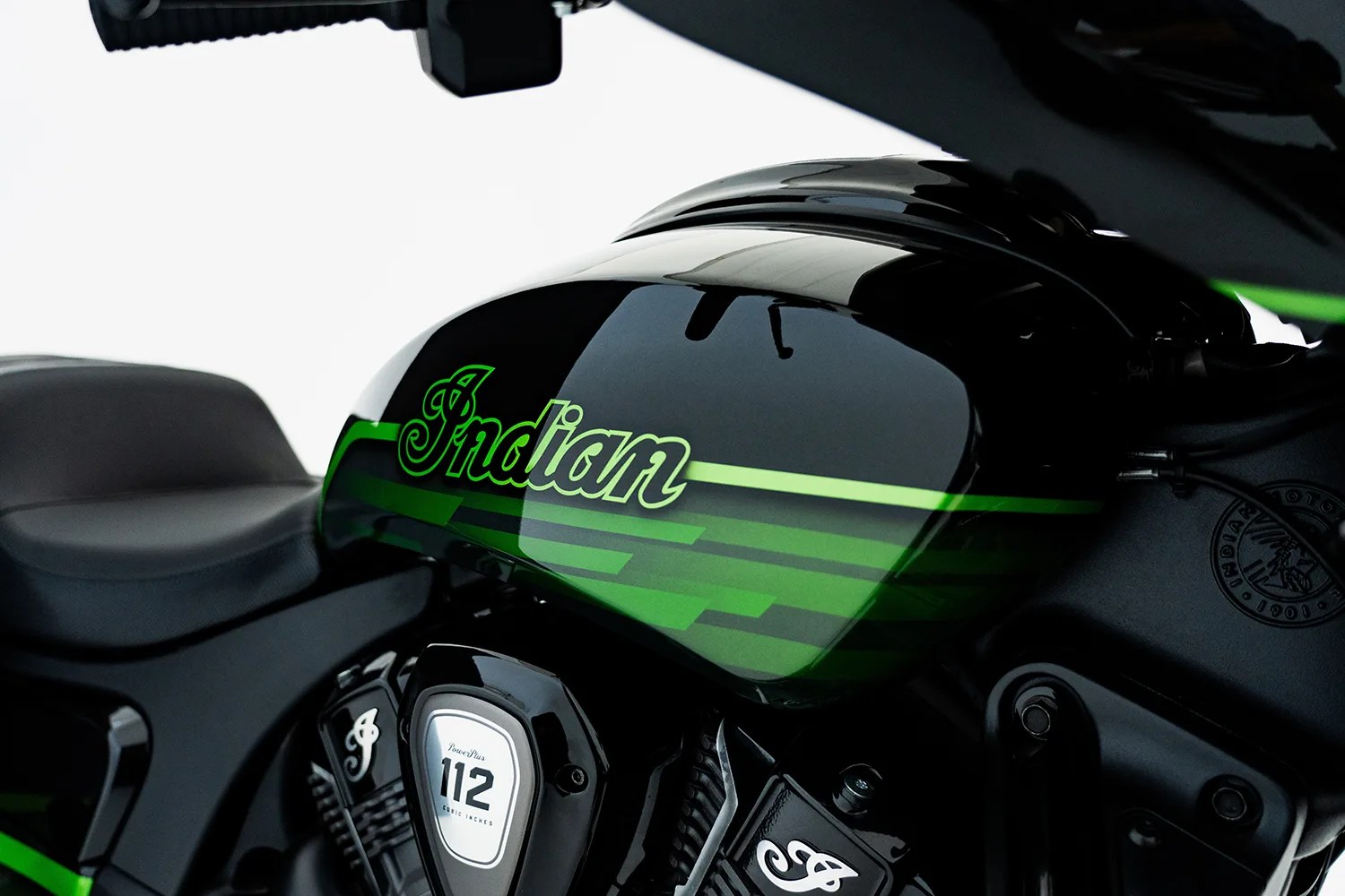 Glossy black motorcycle fuel tank with green stripes and "Indian" logo above a 112 cubic inches engine badge.
