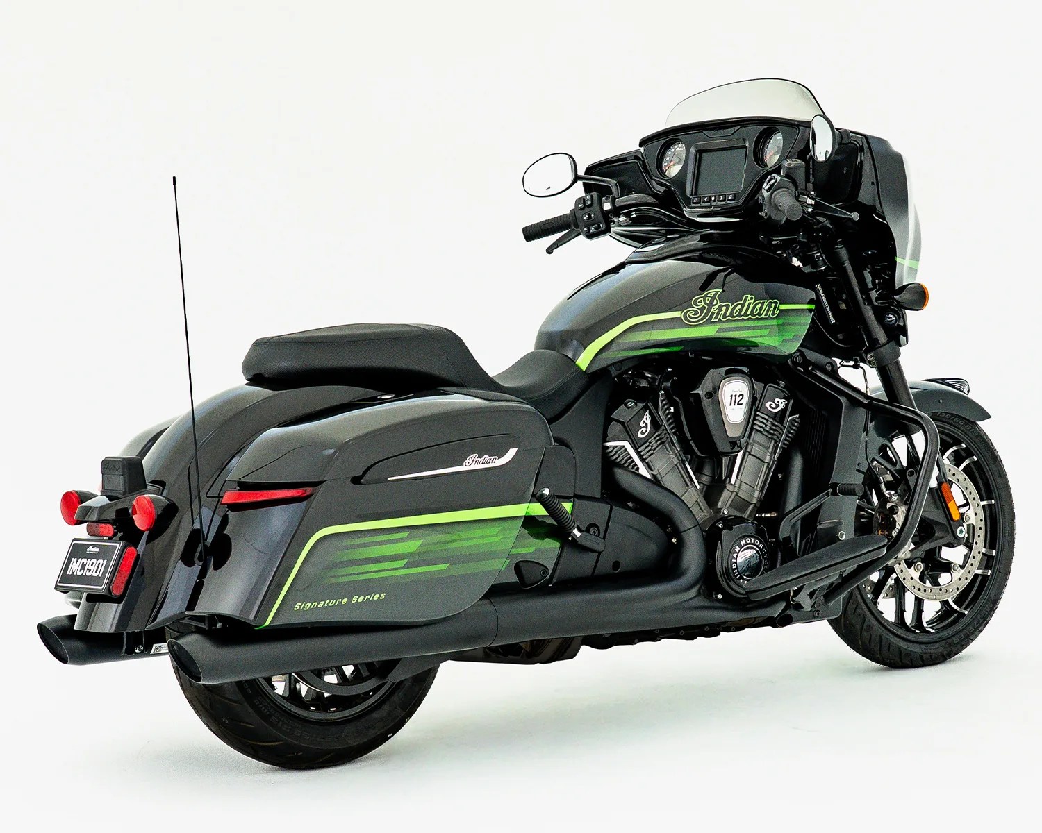 Black Indian motorcycle with green stripes, saddlebags, and a front fairing with dual gauges.